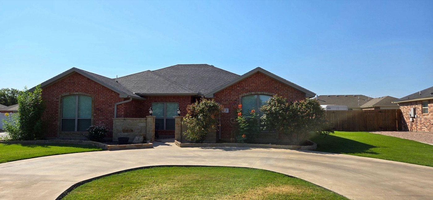 Single-story brick home with a circular driveway and manicured lawn