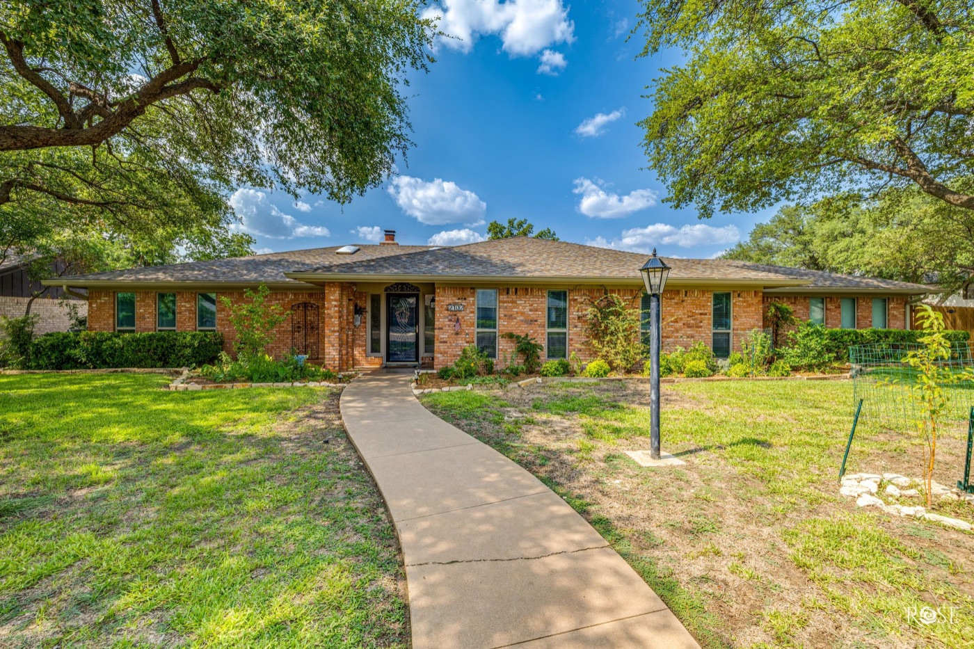 Brick ranch home shaded by mature oak trees