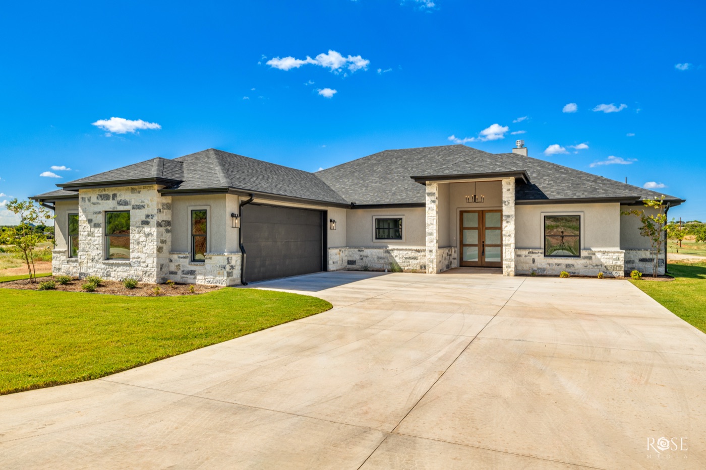 Single-story stone and stucco home with a hipped roof and a wide concrete drive